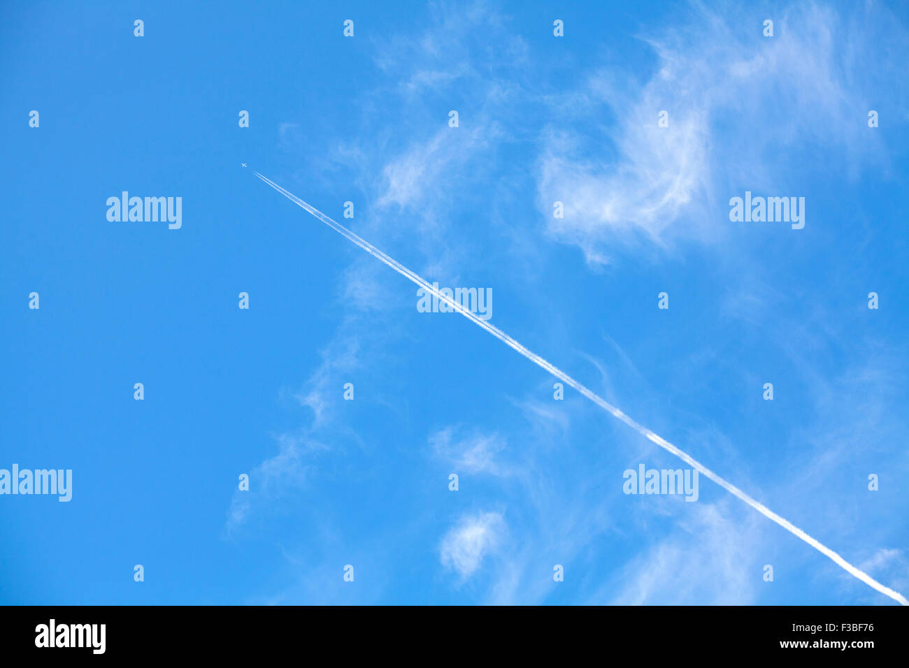 Estelas de condensación de aviones contra el hermoso cielo azul con nubes delicadas, espacio para el texto. Foto de stock