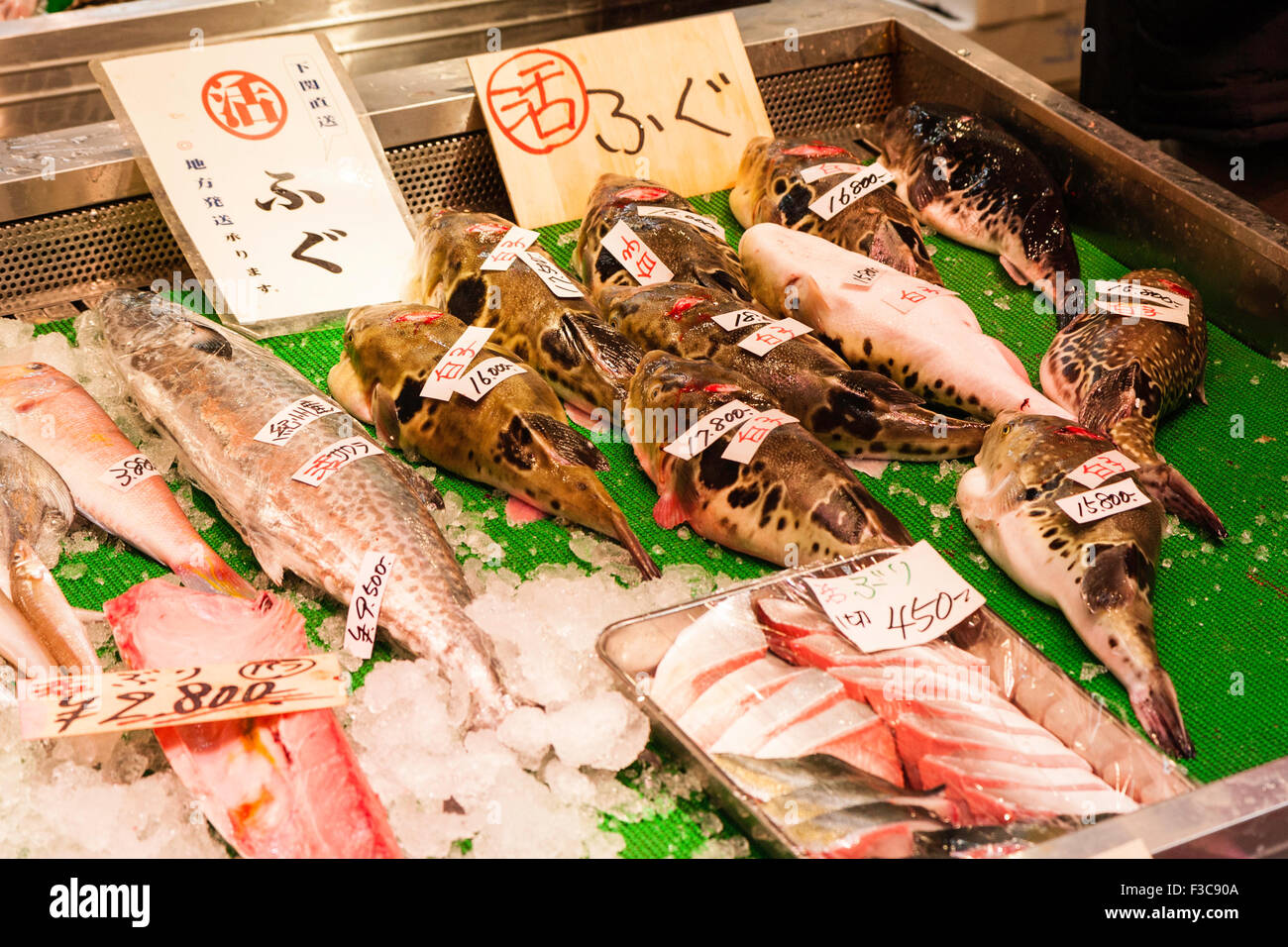 Pez aparece en el stand en el mercado de mariscos Ichiba Kuromon en Osaka.  Algunos de los filetes y demás carne de pescado con varios peces globo,  fugu Fotografía de stock -