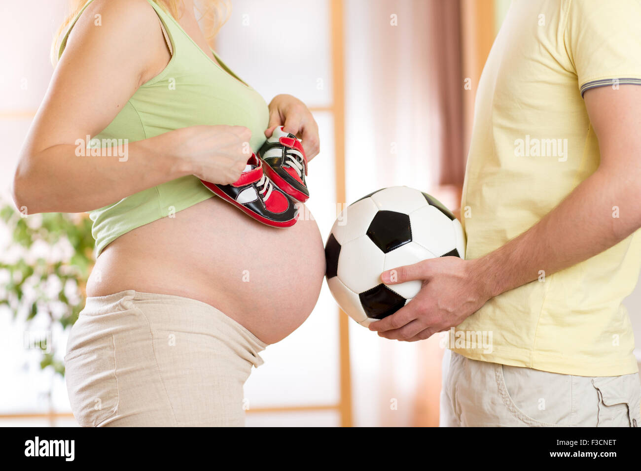 Close-up de una mujer embarazada y su esposo sosteniendo un balón de fútbol Foto de stock