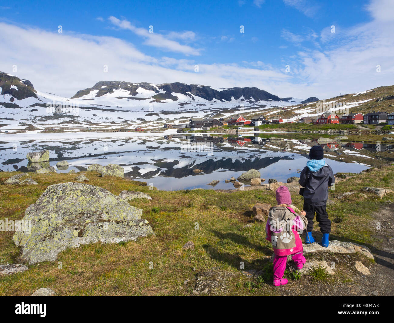 La montaña noruega, panorámica del lago Hardangervidda Finse, Noruega, el hielo y la nieve en el verano, los jóvenes hermanos preparados para una caminata Foto de stock