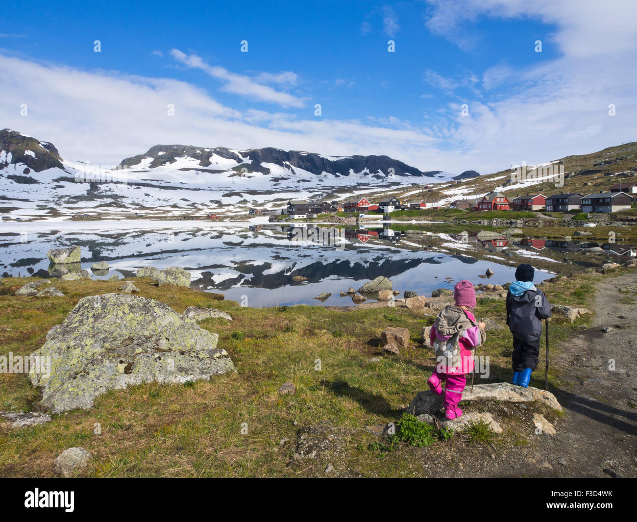 La montaña noruega, panorámica del lago Hardangervidda Finse, Noruega, el hielo y la nieve en el verano, los jóvenes hermanos preparados para una caminata Foto de stock