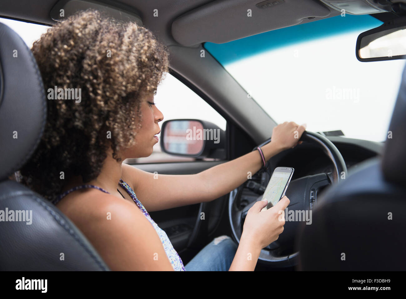 Mujer joven texting mientras se conduce el coche Foto de stock