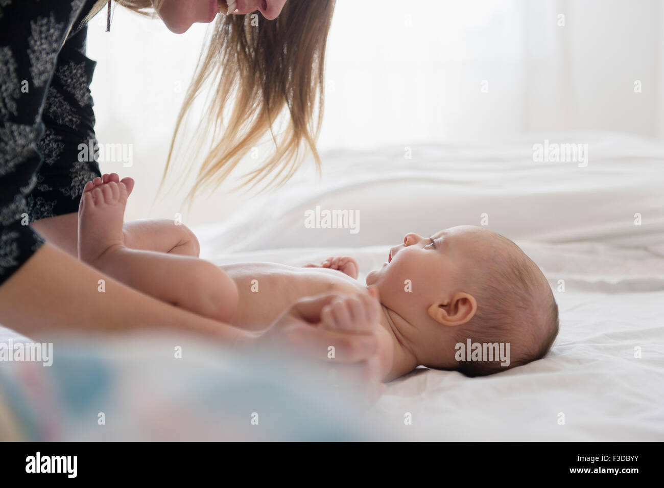 Madre jugando con la niña (2-5 meses) en la cama Foto de stock