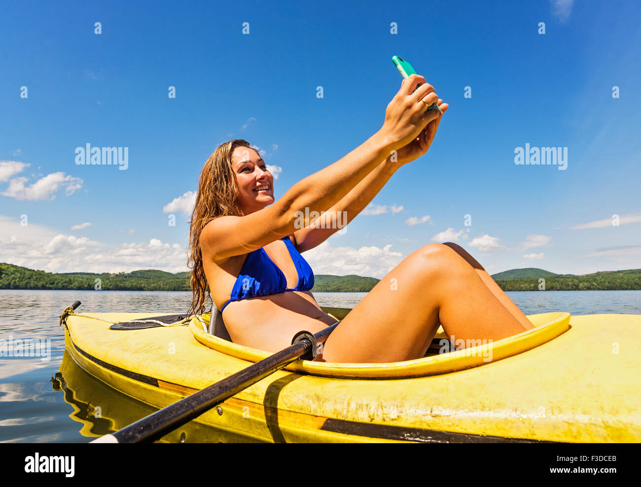 Mujer joven tomando selfie en kayak en el lago Foto de stock