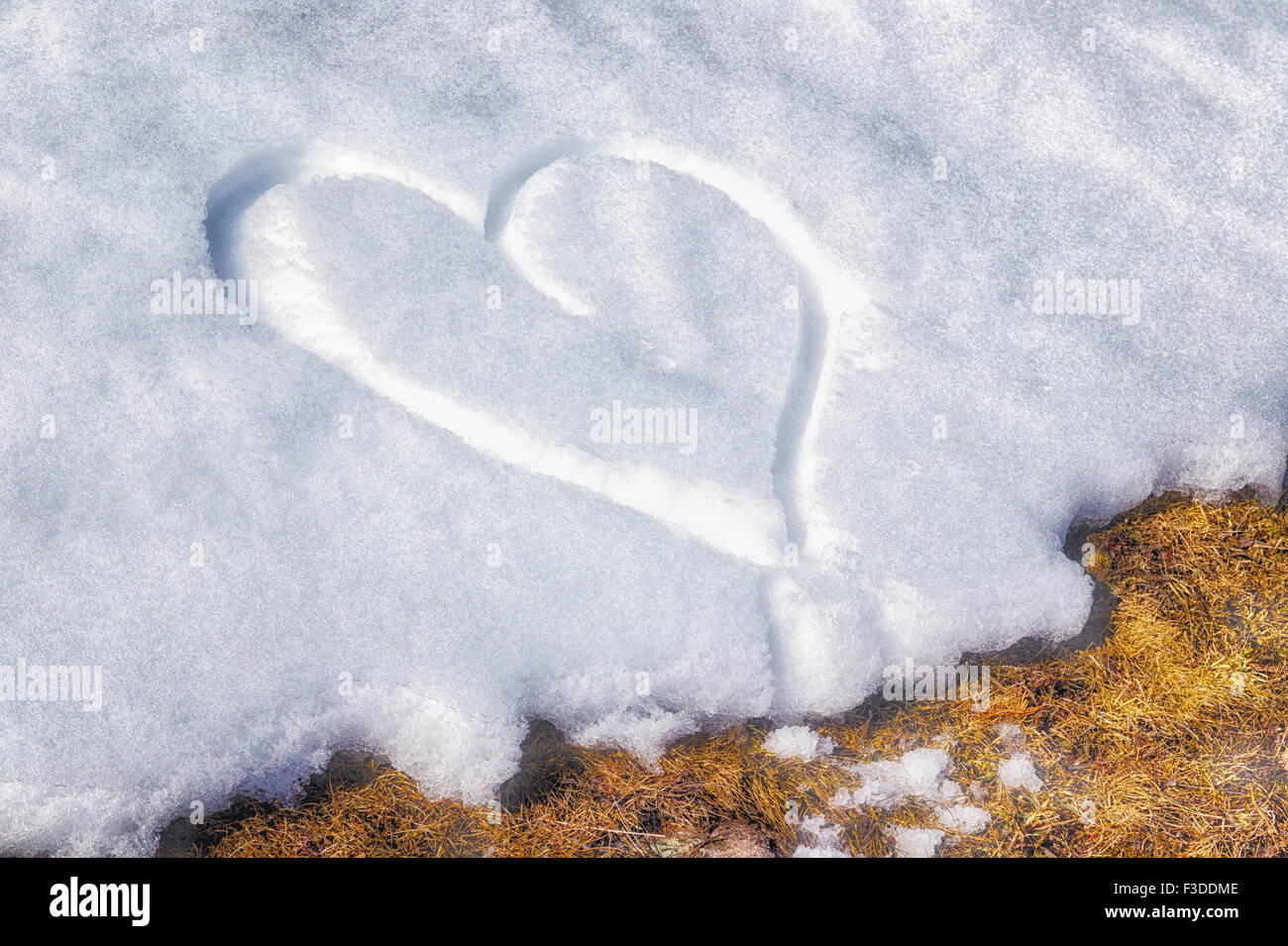 Un corazón dibujado a mano en la nieve fresca Foto de stock