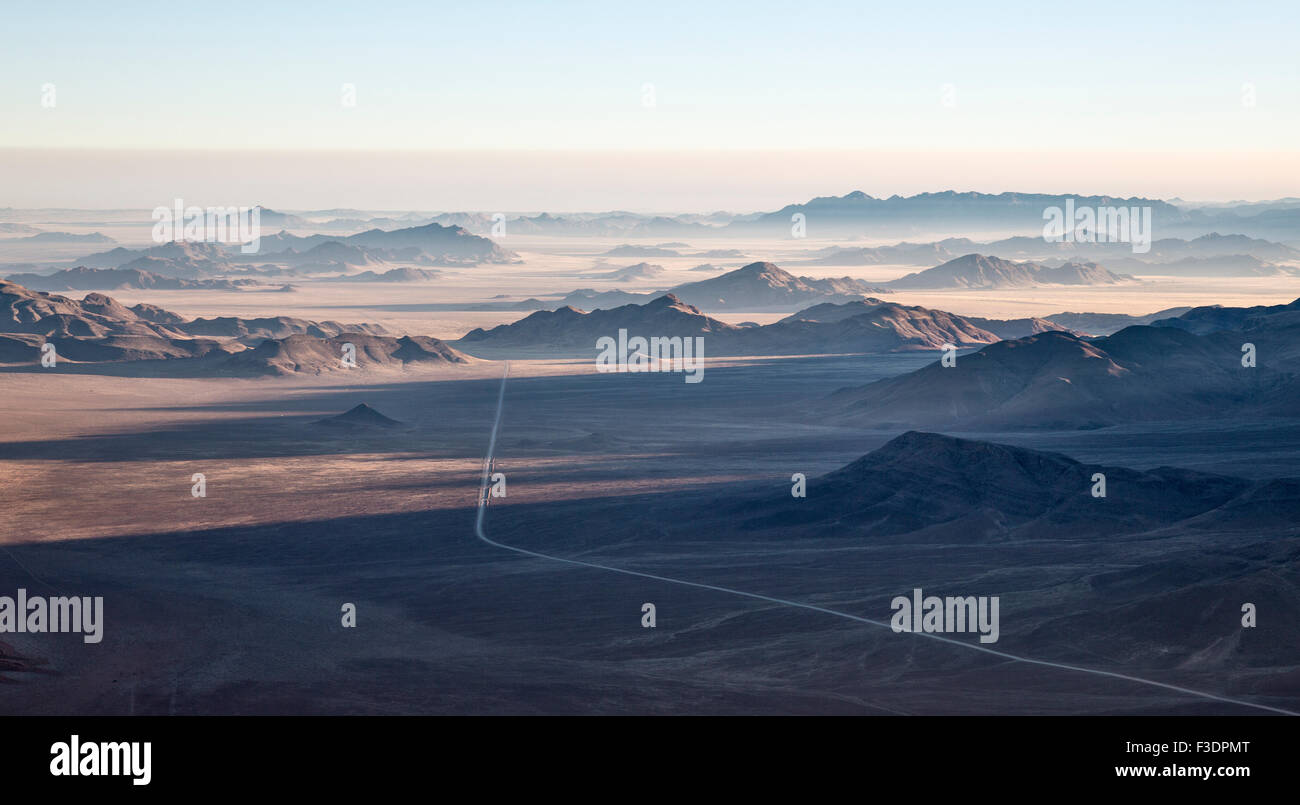 Las crestas de las montañas aisladas y C27 carretera de grava, el borde del desierto de Namib, niebla costera detrás, vista aérea, Reserva Natural NamibRand Foto de stock