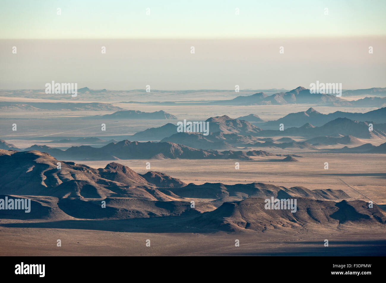 Las crestas de las montañas aisladas y C27 carretera de grava, el borde del desierto de Namib, niebla costera detrás, vista aérea, Reserva Natural NamibRand Foto de stock