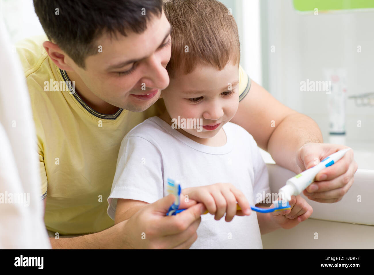 Niño y su papá cepillarse los dientes en el baño. Foto de stock
