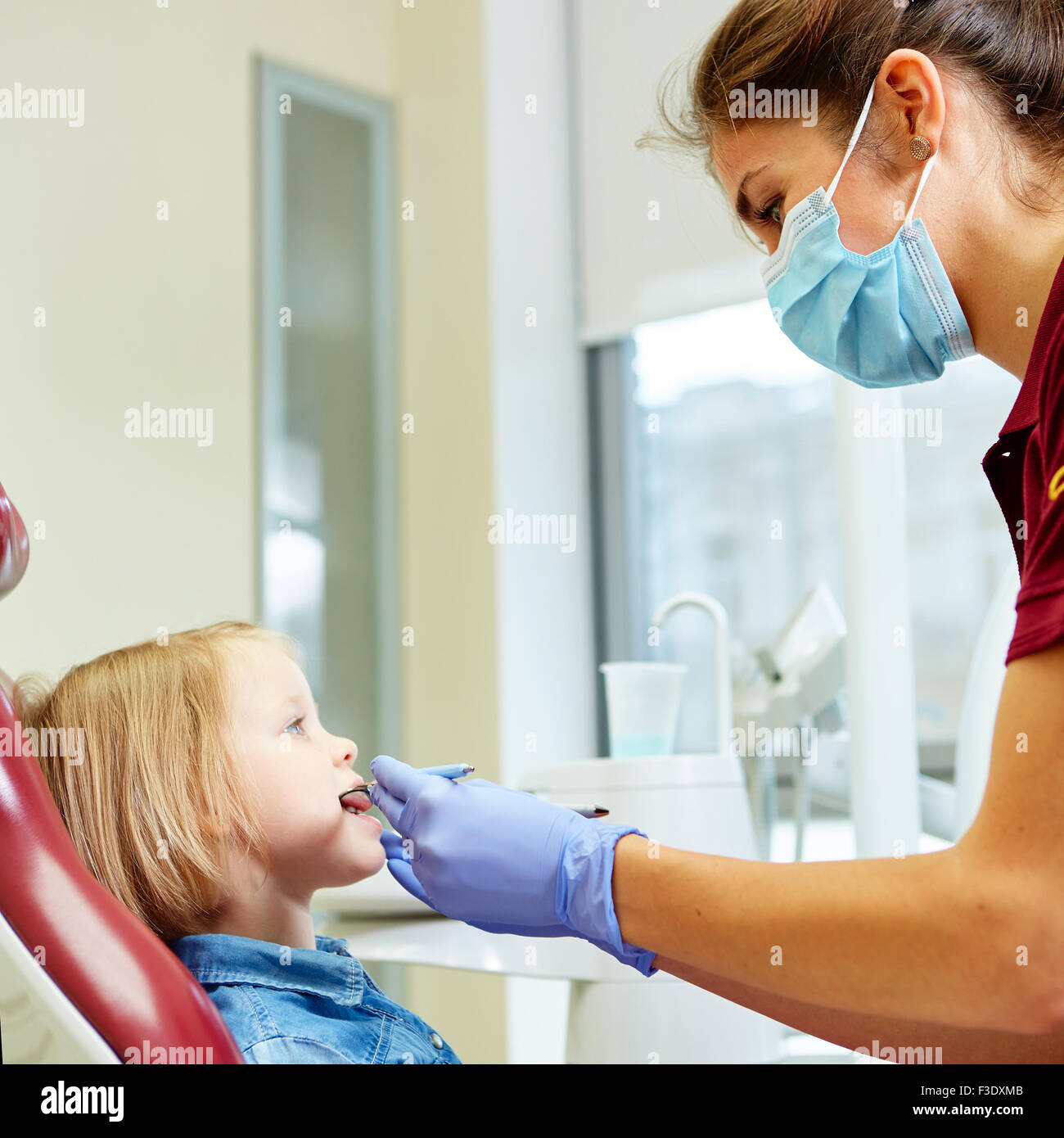 Dentista pediátrico examinando las niñas dentistas dientes en la silla