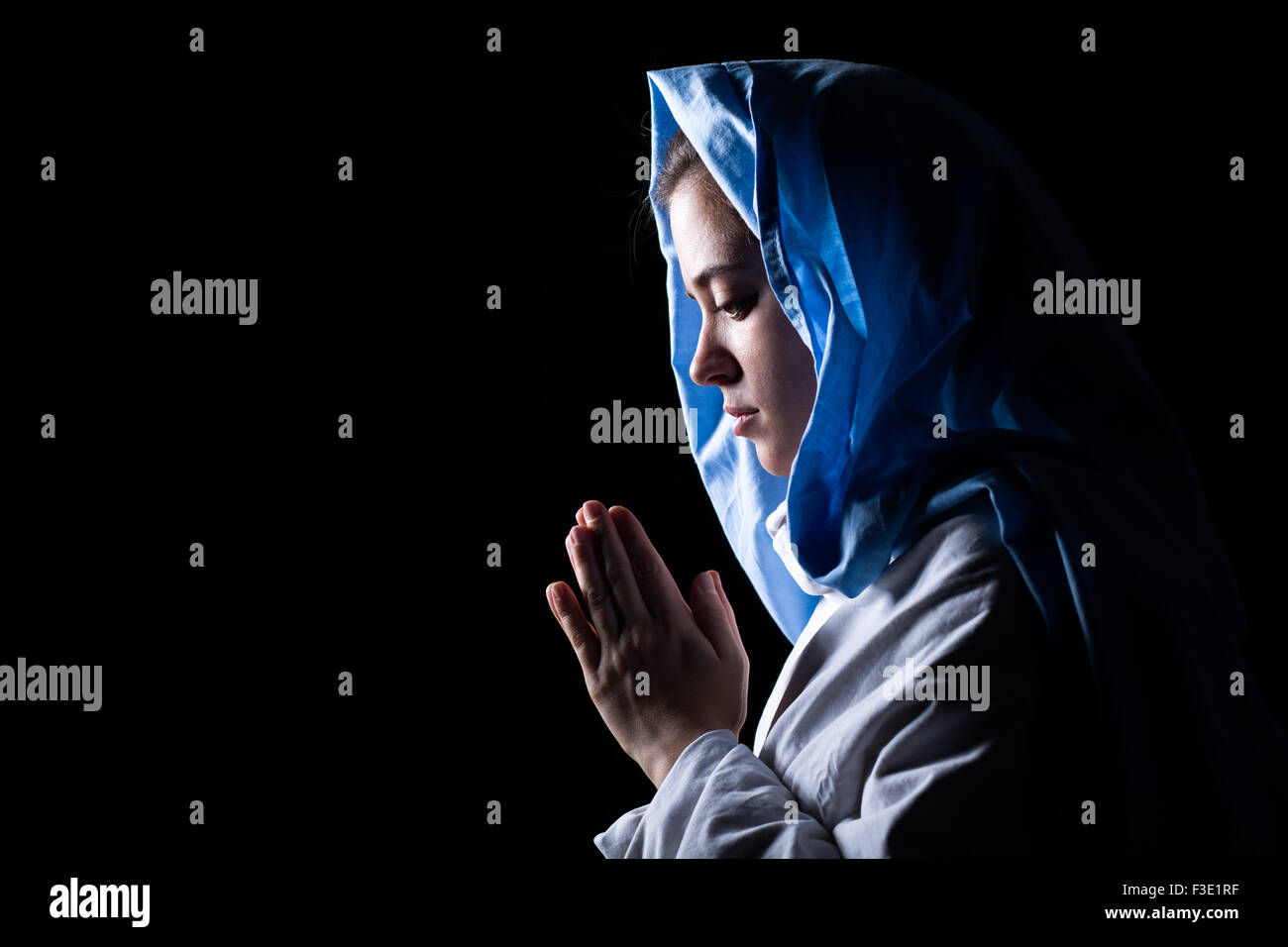 Virgen María rezando con velo azul sobre fondo negro Fotografía de stock -  Alamy