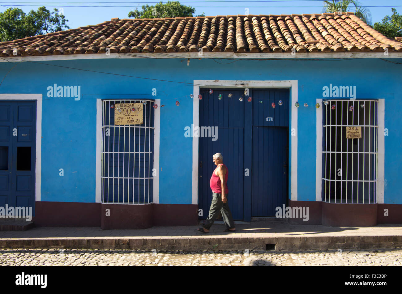 La mujer camina pasado una tradicional casa de estilo colonial español con ventanas con barrotes en Trinidad, provincia de Sancti Spiritus Foto de stock