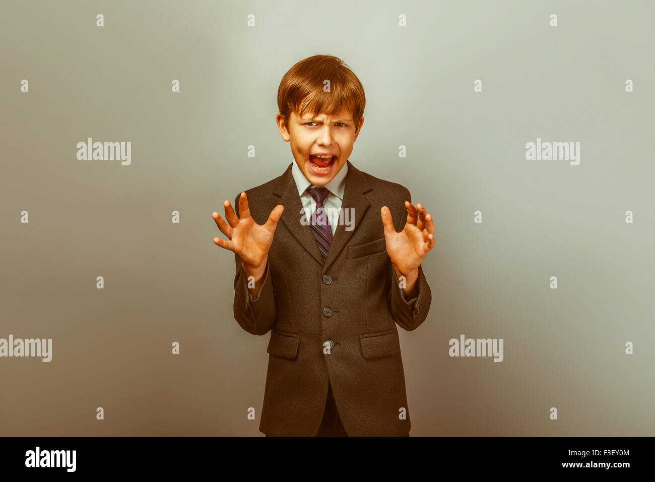 Un muchacho de doce en un traje de apariencia europea gritando enojado en Foto de stock