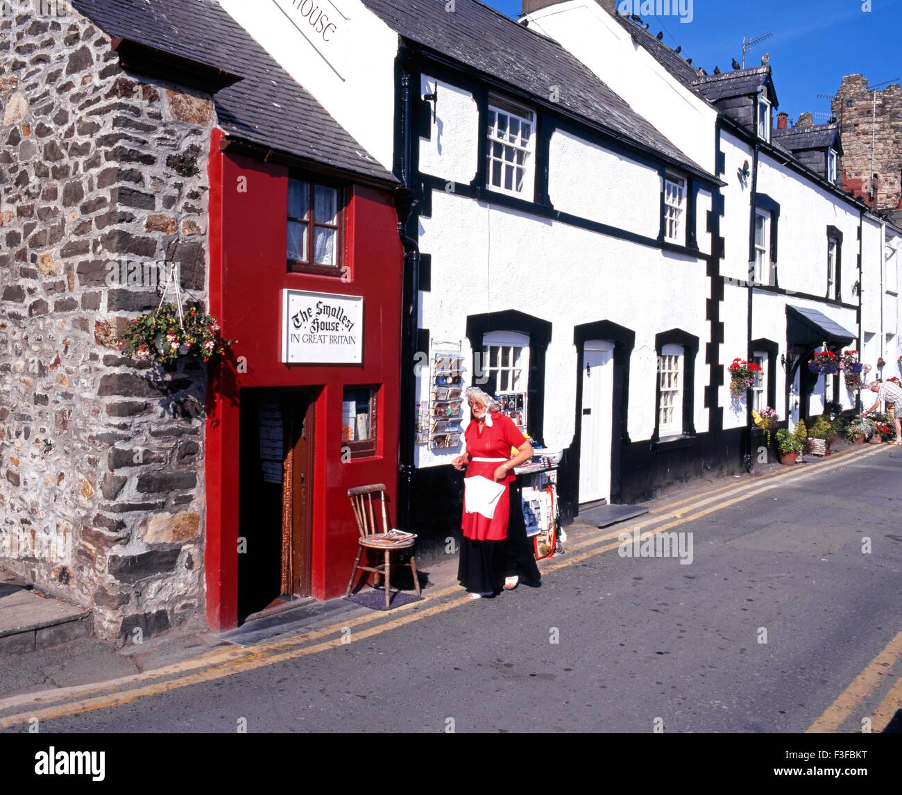 La casa más pequeña de Gran Bretaña con una dama galés en traje tradicional en el primer plano, Conwy, Gwynedd, Gales, Reino Unido. Foto de stock
