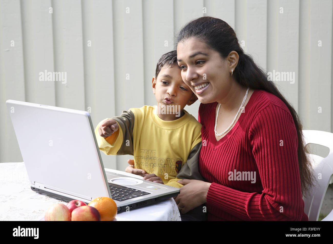 Chico apuntando con el dedo índice con la madre mirando a la pantalla del portátil se tocan los jefes MR#468 Foto de stock