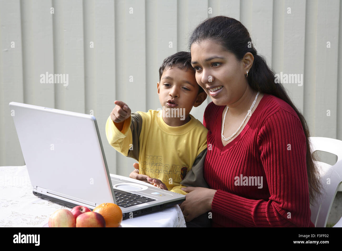Chico apuntando con el dedo índice con la madre mirando a la pantalla del portátil se tocan los jefes MR#468 Foto de stock