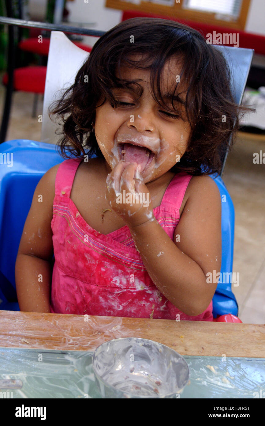 Dos años Baby Girl propagación dahi en la mesa mientras comen y disfrutando de MR#0543 Foto de stock