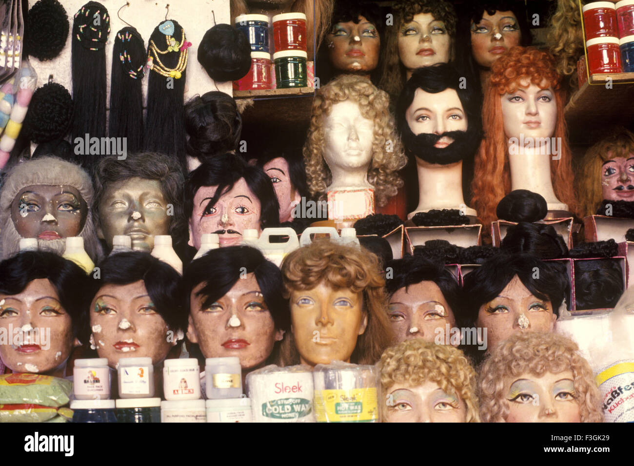 Pelucas, barbas, bigotes y cabello aparece en máscaras faciales junto con productos cosméticos en una tienda de belleza Mumbai Foto de stock