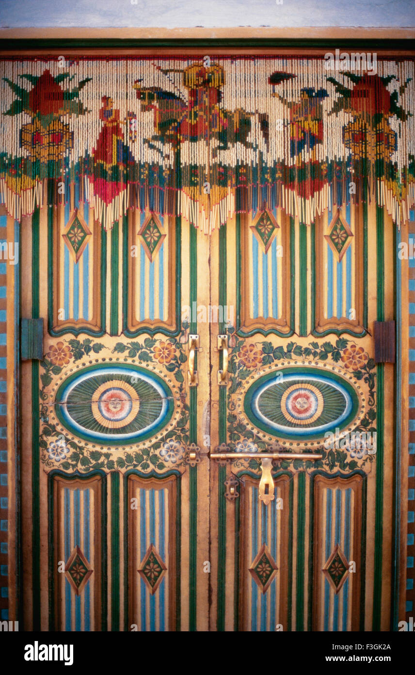 Gráficamente la puerta de madera pintada con tubos de vidrio y cordón colgando de una 'casa de kathi'; en estilo típicamente Kathiawar Rajkot Foto de stock