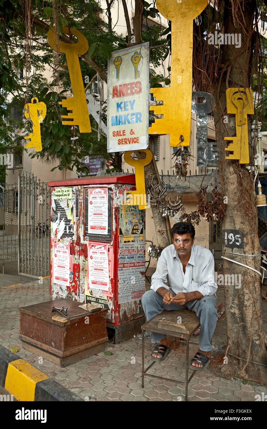 Una clave duplicada maker configurando su tienda bajo un árbol con una pantalla de enormes recortes clave para atraer clientes ; Mumbai Foto de stock