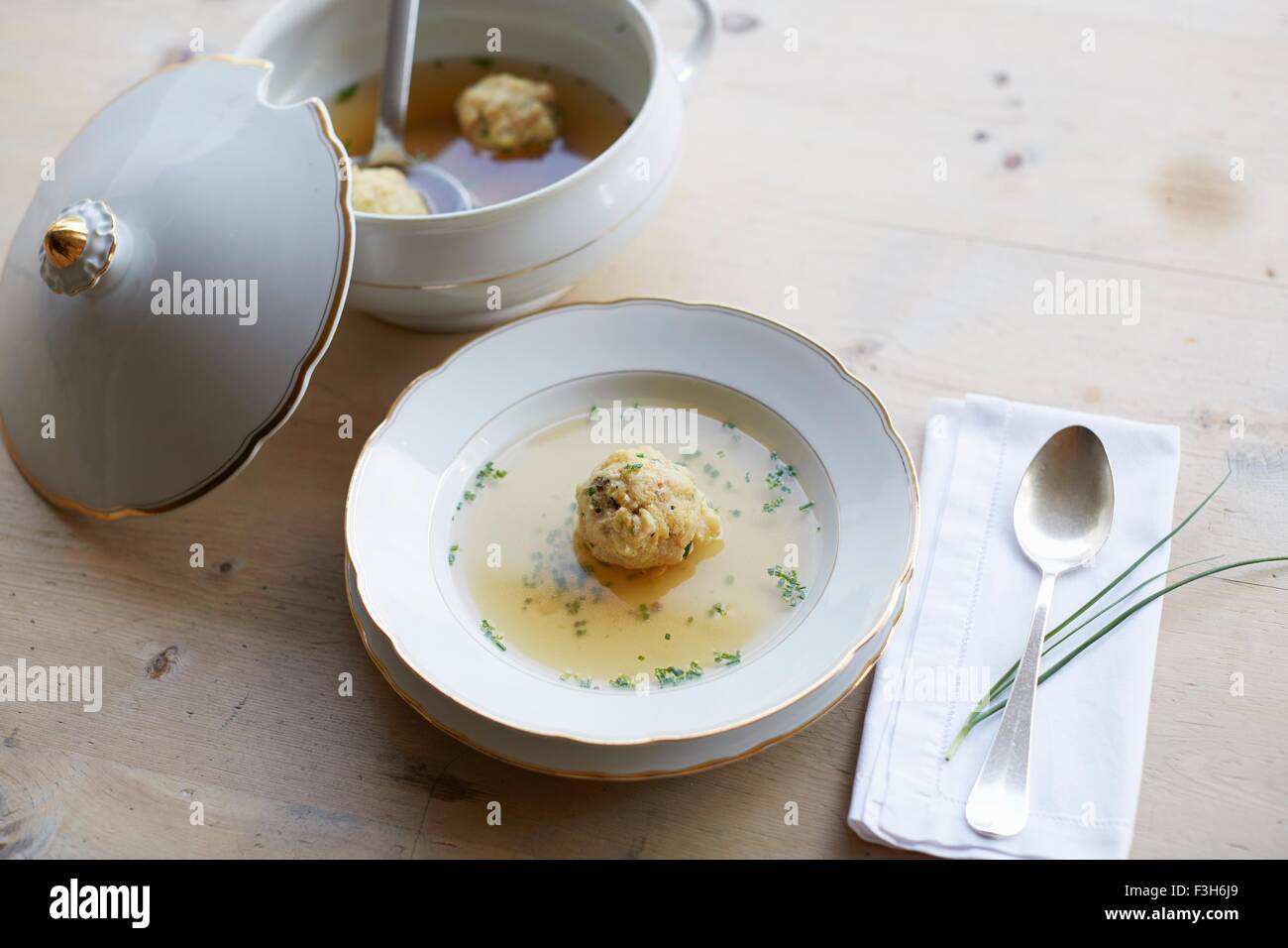 Tabla con sopa fresca y dumpling en un tazón Foto de stock