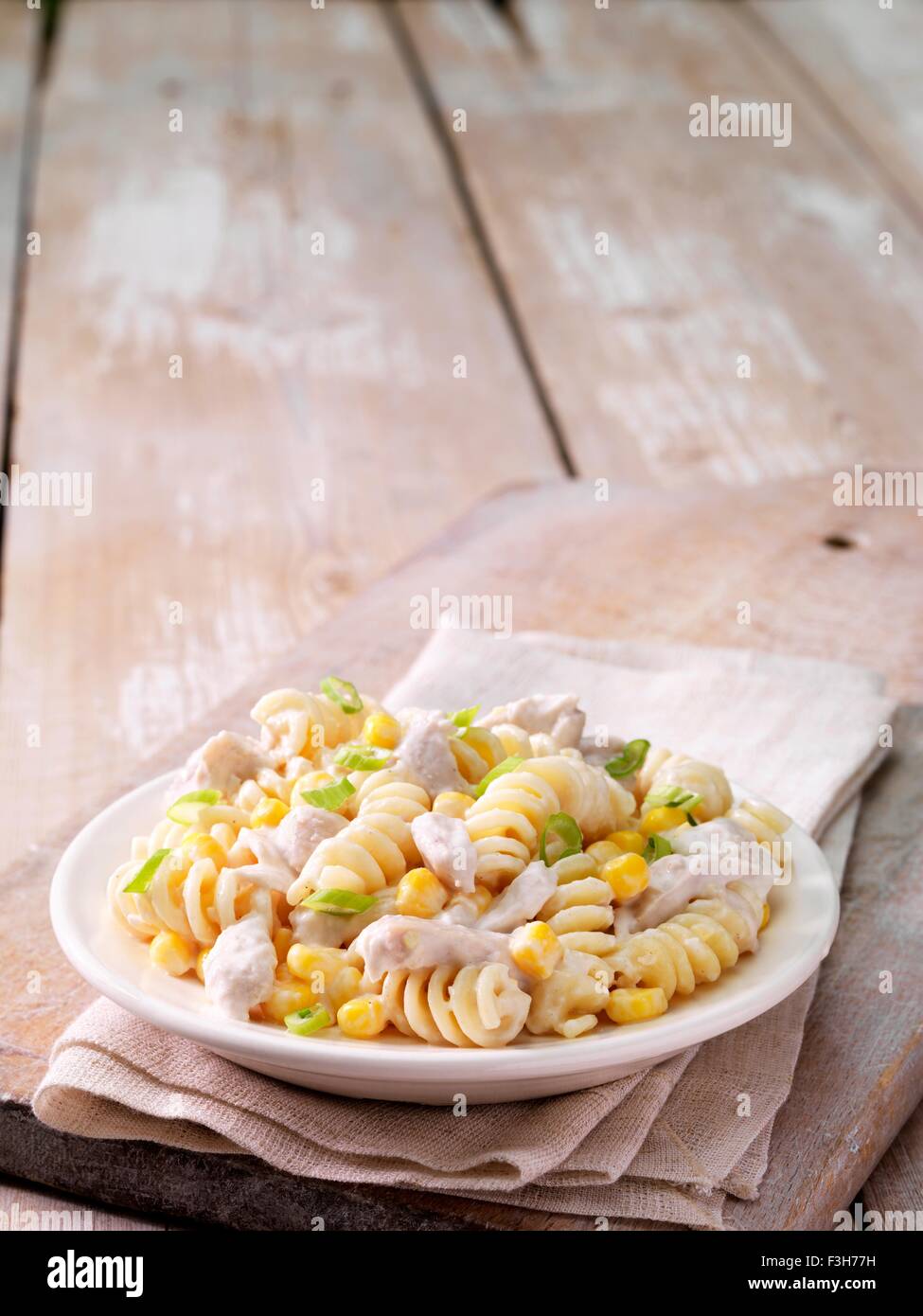 Still life de pollo y maíz dulce pasta con cebolla aderezo en un tazón Foto de stock