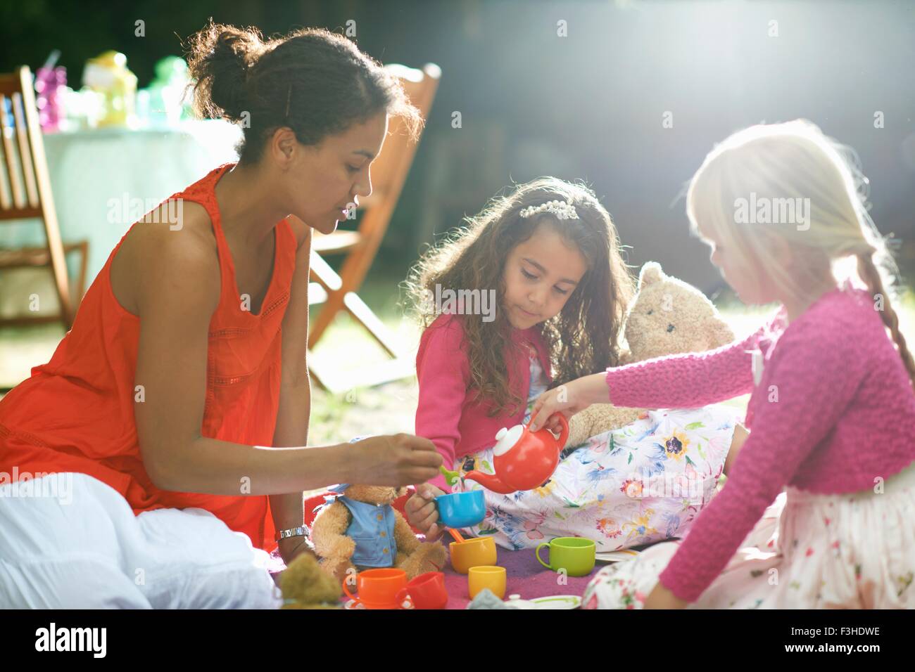 La madre y dos niñas juegan el picnic en el jardín fiesta de cumpleaños Foto de stock