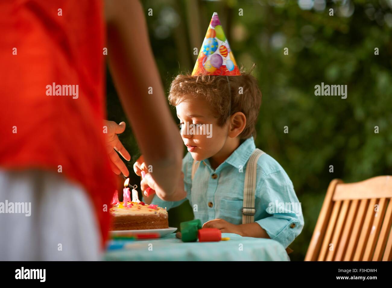 Madre con su hijo soplando las velas en el pastel de cumpleaños en el jardín fiesta de cumpleaños Foto de stock
