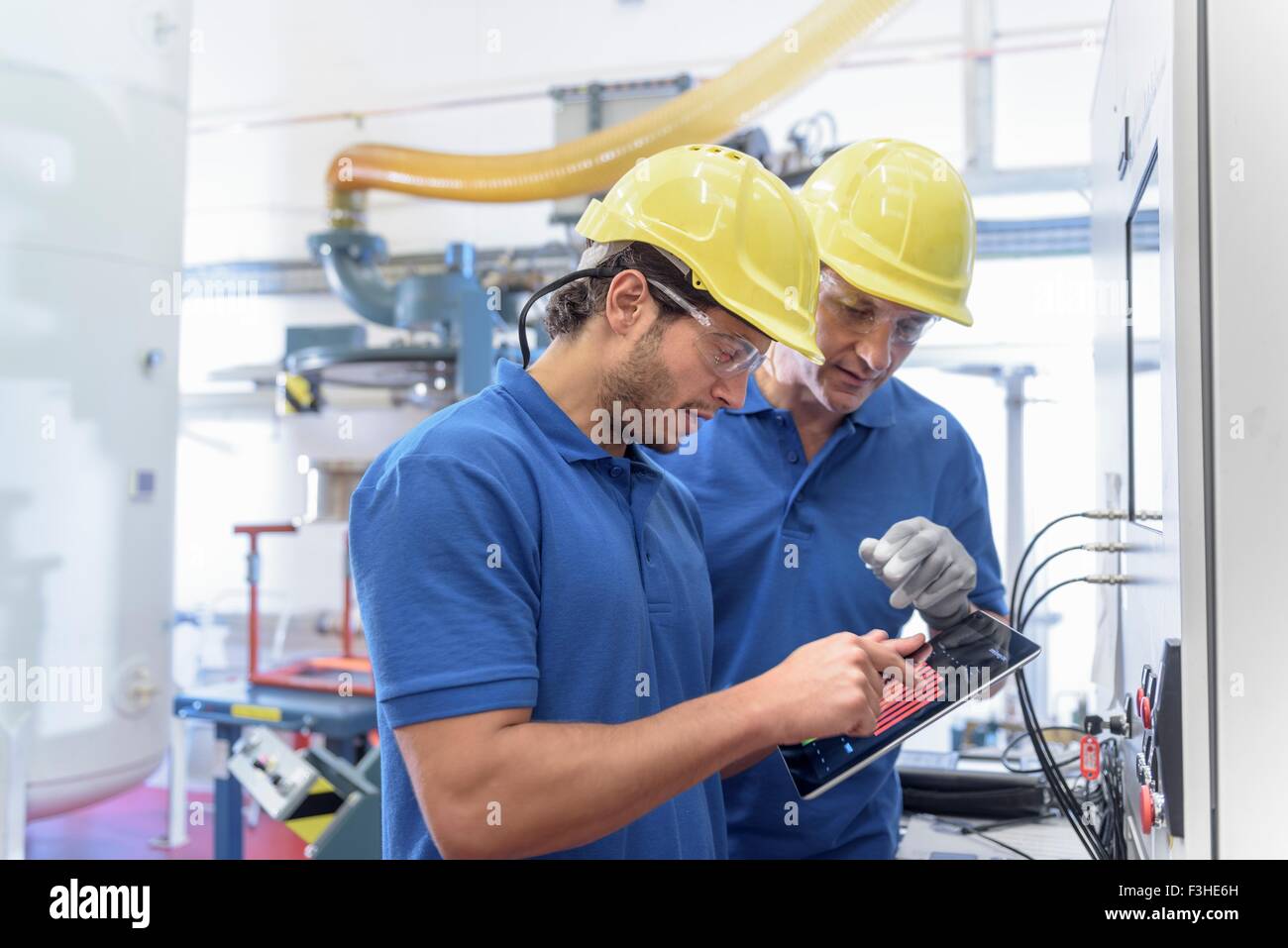 Los trabajadores que operan con equipos de pruebas ambientales en tableta digital electrónica fábrica Foto de stock