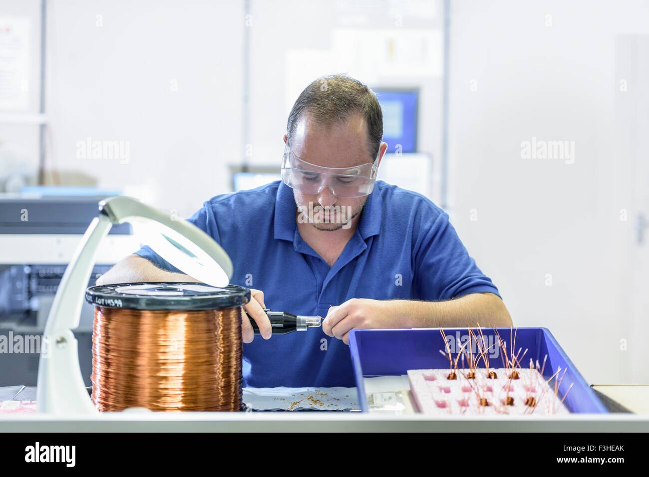 Trabajador masculino Montaje de bobinas electromagnéticas en electrónica fábrica Foto de stock