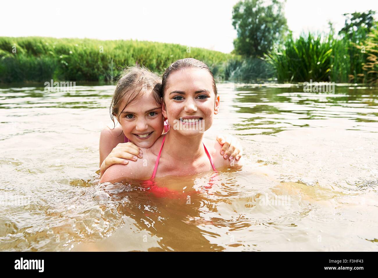 Retrato de una adolescente y su hermana la natación en el lago rural Foto de stock