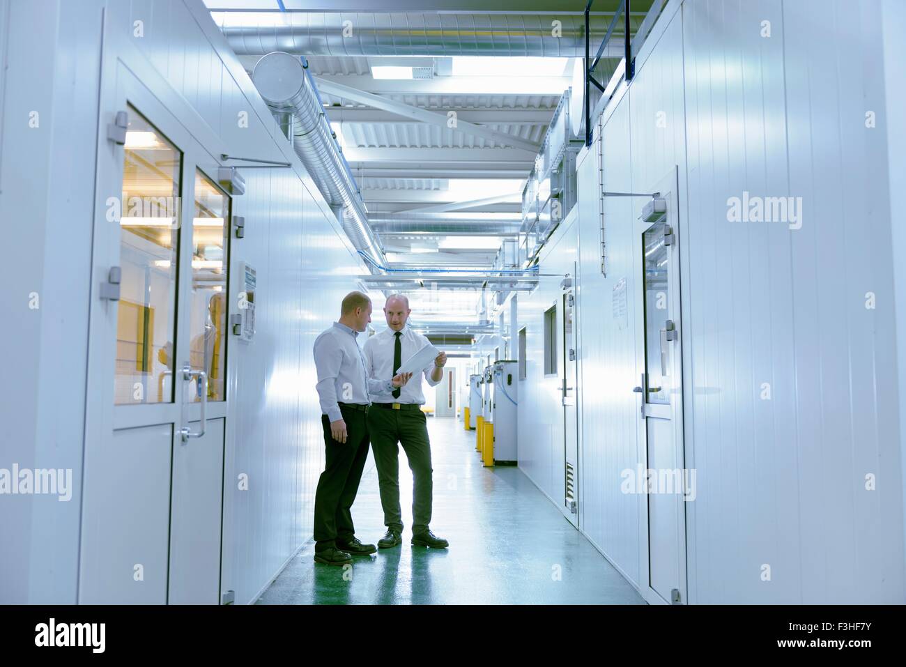Los gerentes inspeccionando robotic cabinas de pulverización de pintura de fábrica de piezas de automoción Foto de stock