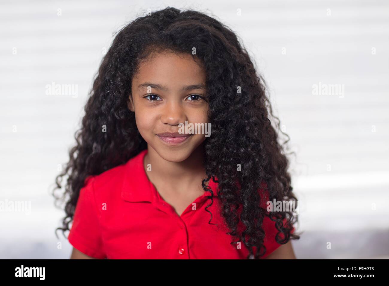 Retrato de la chica con el cabello negro rizado mirando a la cámara sonriendo Foto de stock