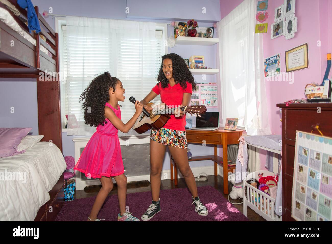 Las niñas en la habitación hacia el micrófono cantando y tocando la guitarra Foto de stock