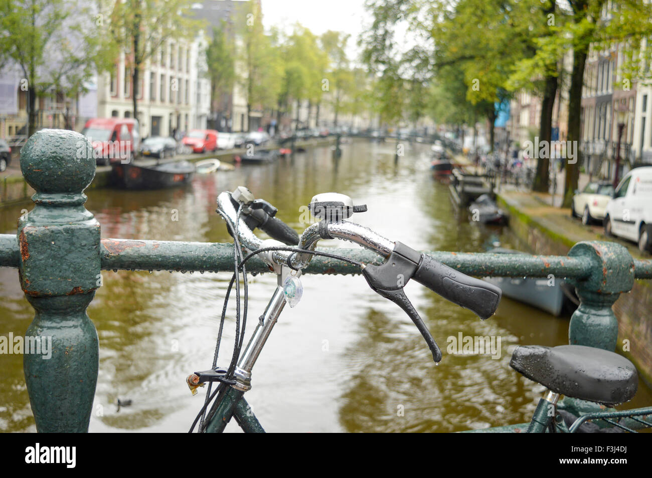 Bicicleta estacionada sobre un puente en Amsterdam en un día lluvioso Foto de stock