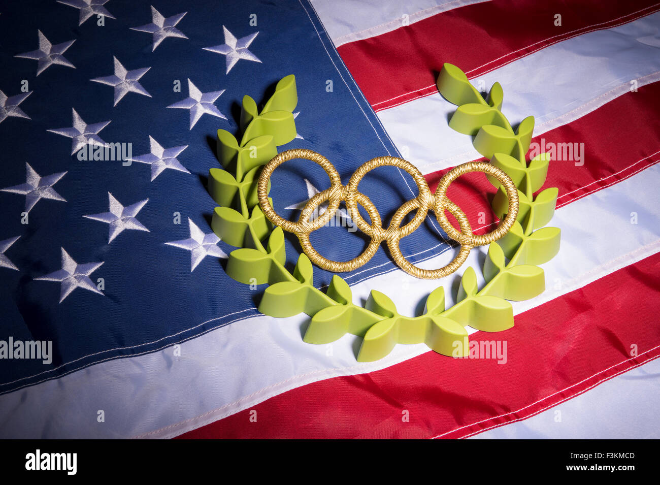 Río de Janeiro, Brasil - Febrero 3, 2015: Oro anillos olímpicos resto con corona de laurel sobre la bandera americana de fondo. Foto de stock