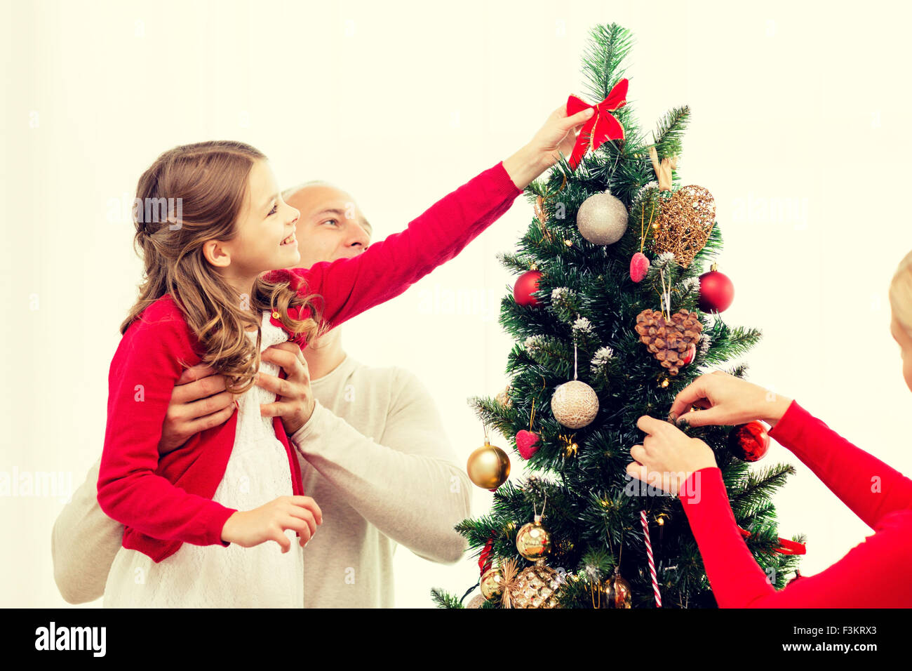 Familia sonriente decorar árbol de navidad en casa Foto de stock