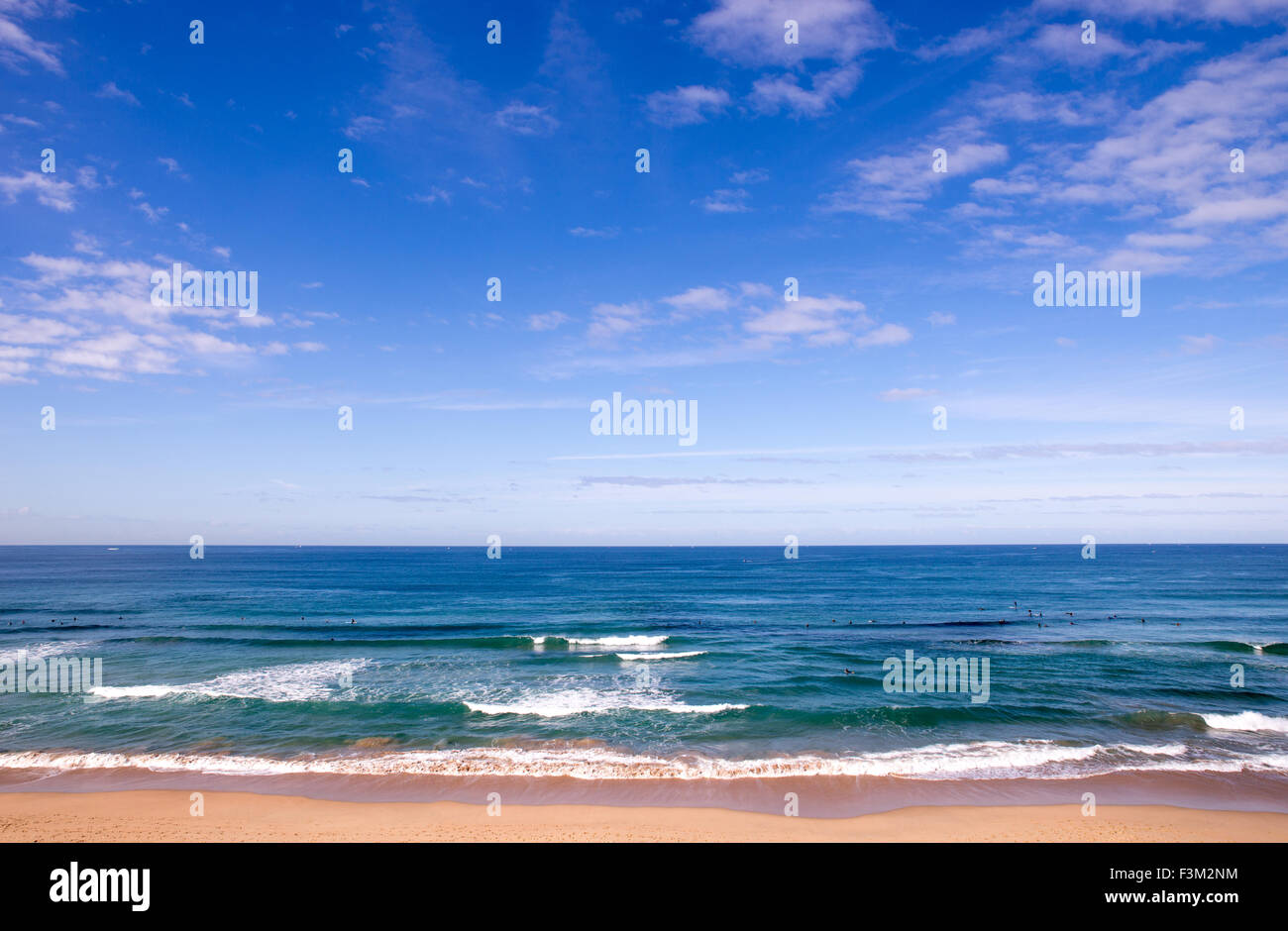 La Playa de Cronulla en Sydney, Australia, con nadadores, las nubes y las olas del océano azul Foto de stock