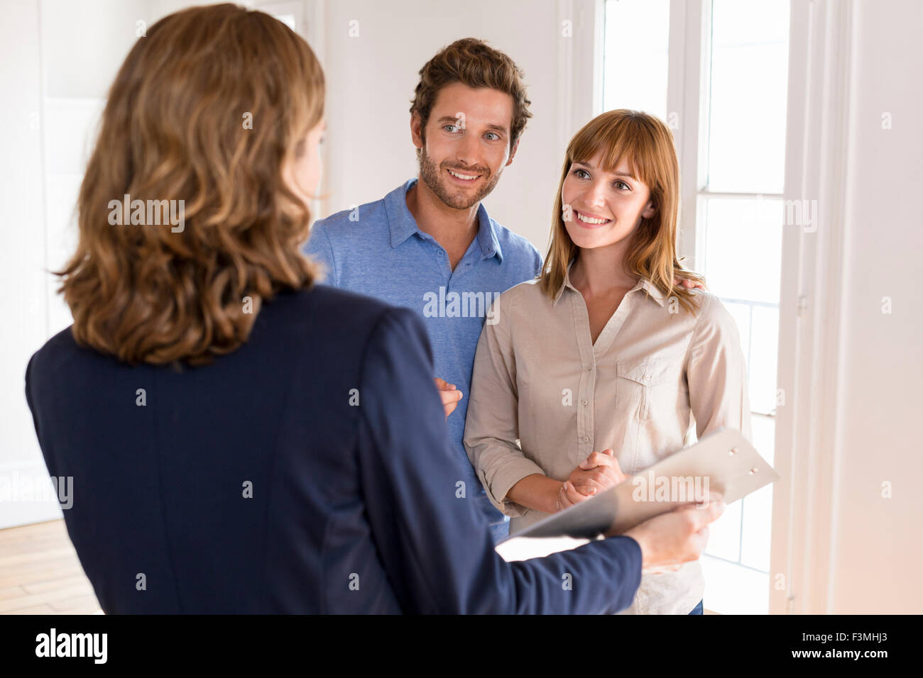 Pareja joven visitando apartamento con real estate agent Foto de stock