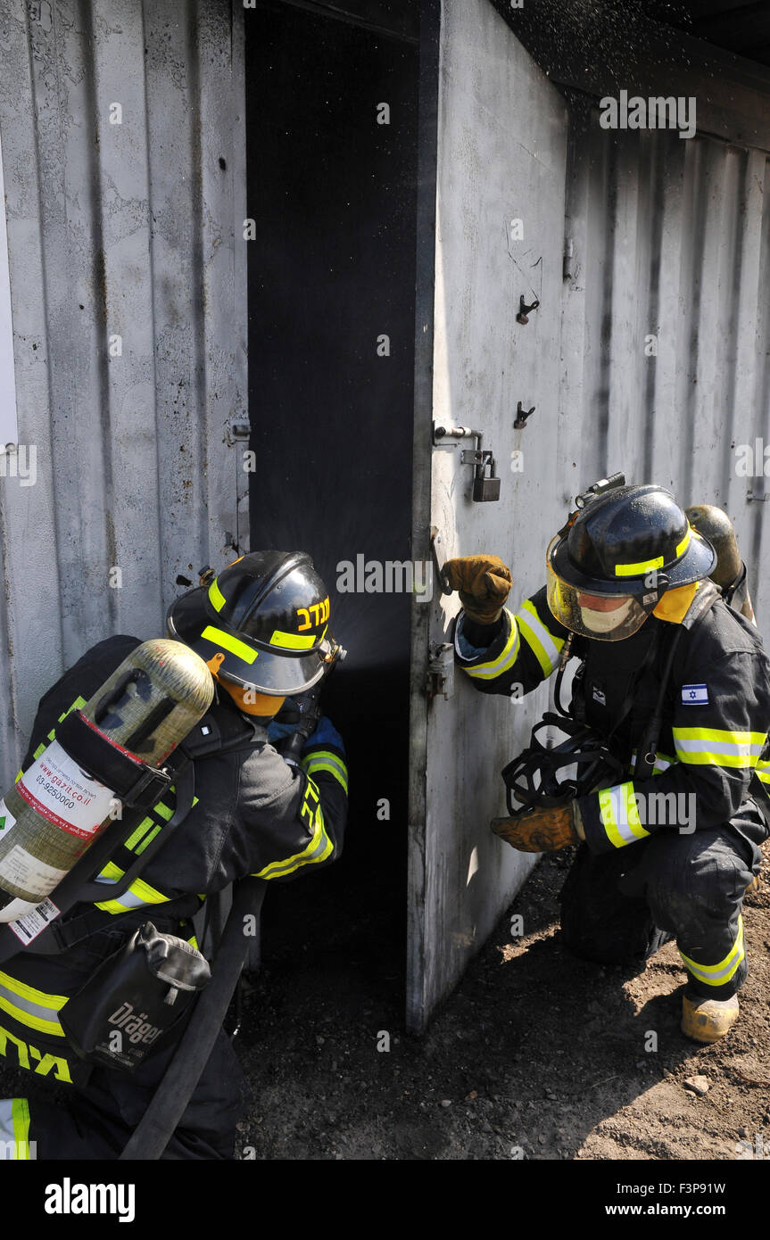 Los bomberos con equipos de protección se preparan para entrar en una habitación llena de humo Foto de stock