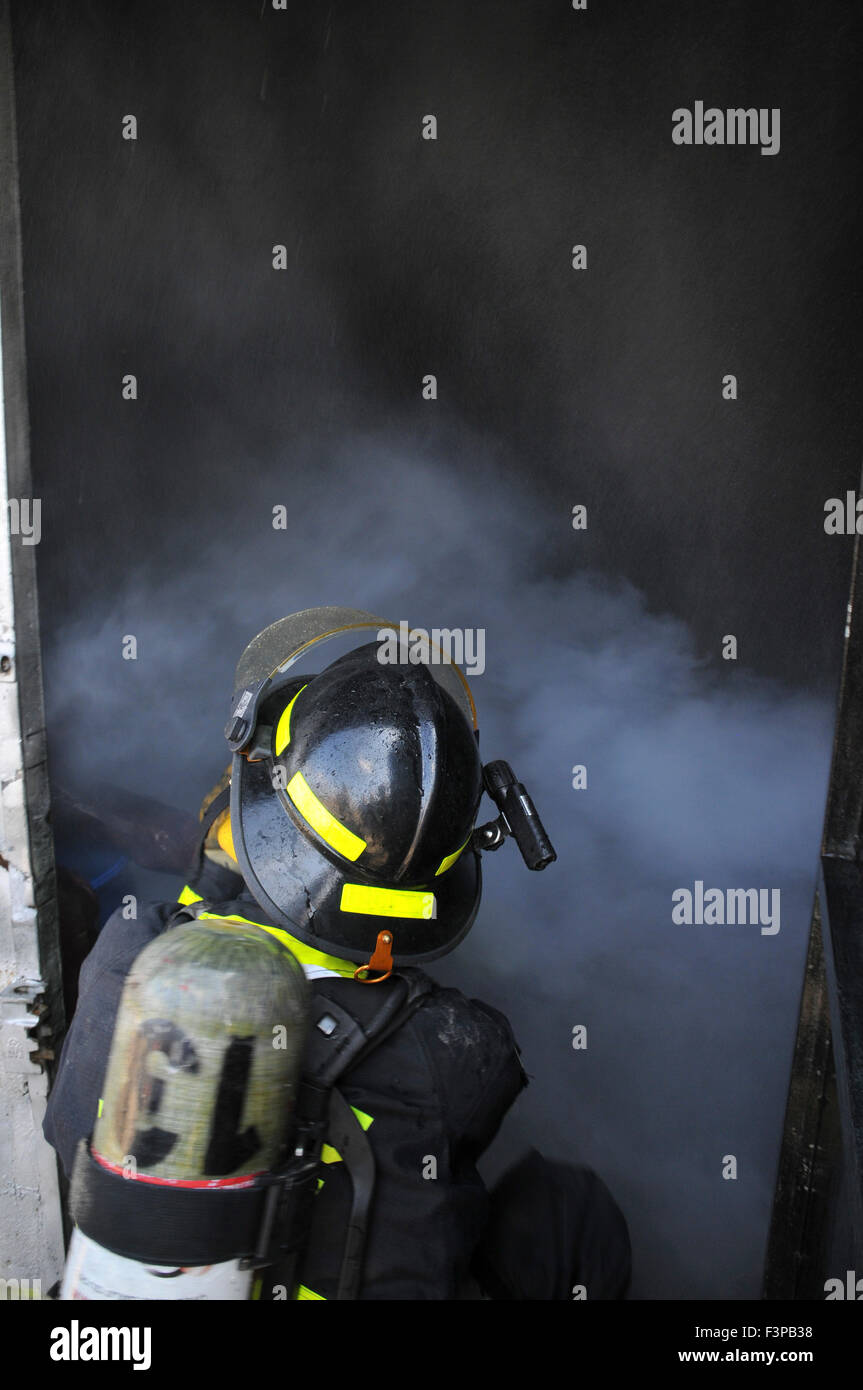 Los bomberos con equipos de protección en una habitación llena de humo Foto de stock