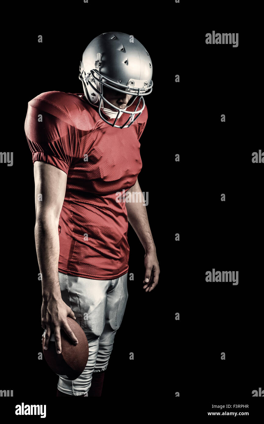 Imagen compuesta de jugador de fútbol americano con bola mirando hacia abajo Foto de stock