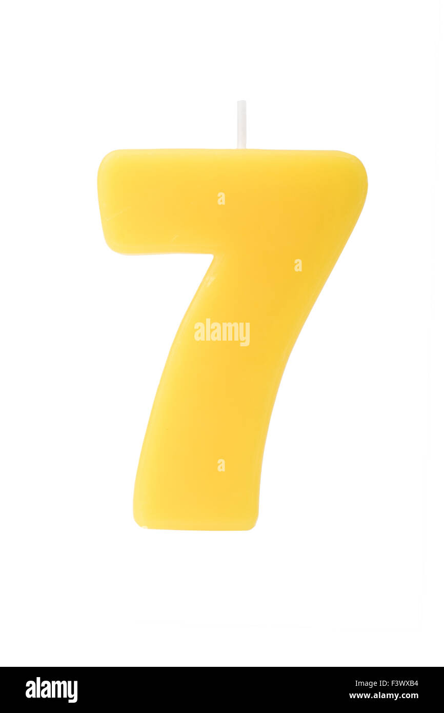 Amarillo vela de cumpleaños en forma del número siete sobre fondo blanco. Foto de stock