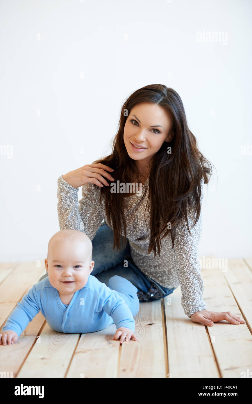 A la madre y al bebé en el piso mirando a la cámara Foto de stock