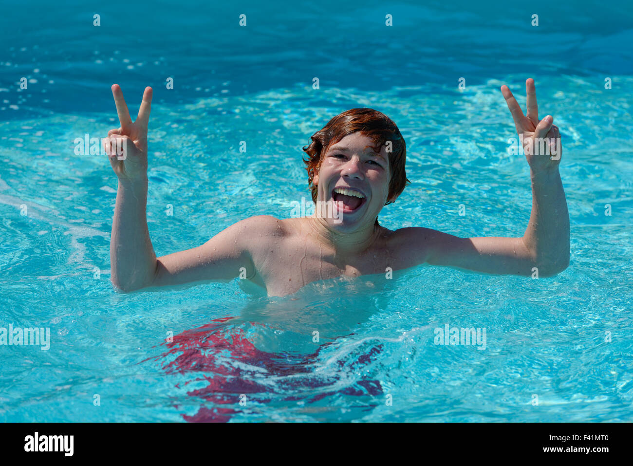 Adolescente en el agua, feliz, signo de paz, signo de la victoria, en una piscina Foto de stock