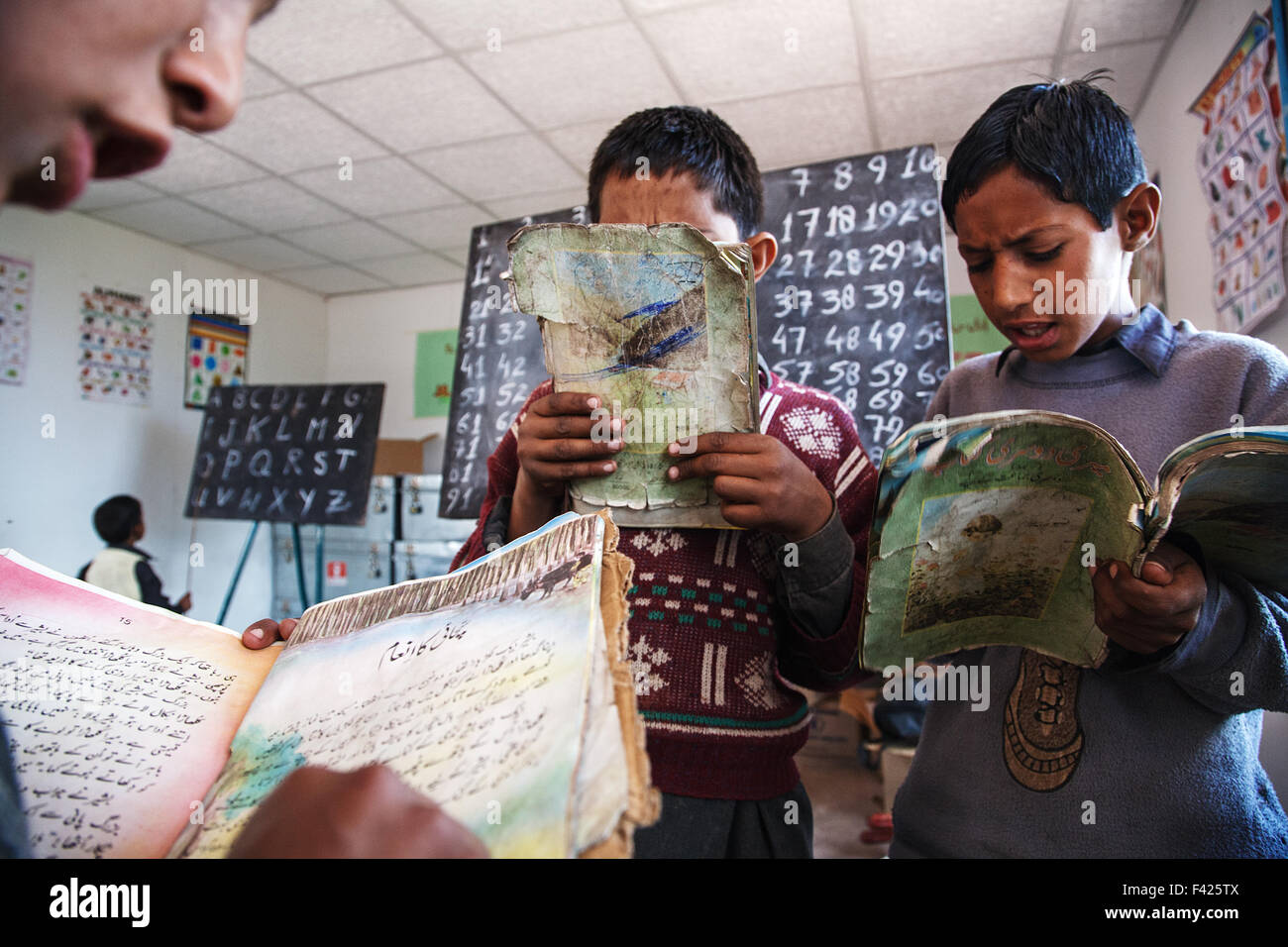 Younf alumnos la lectura de los libros de texto durante una clase en una escuela primaria cerca de Muzaffarabad, en Cachemira, en Pakistán. Foto de stock