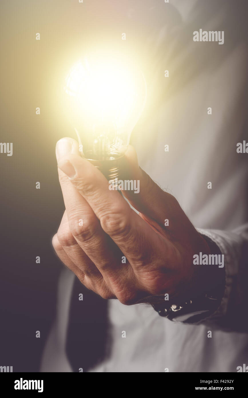 La educación de las nuevas ideas a la empresa, empresario con bombilla ofreciendo nuevas soluciones a problemas de comprensión en los negocios, Foto de stock