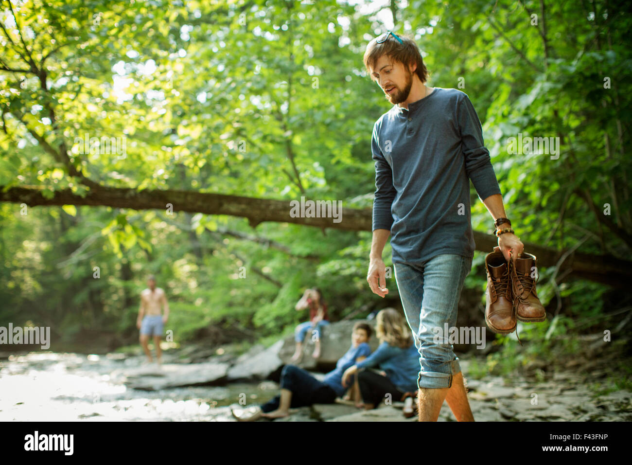 el hombre con ropa de senderismo se sentó en un viejo tronco en el bosque,  rechaza la bota de goma que le quita el polvo. concepto de estilo de vida  activo. 16281158