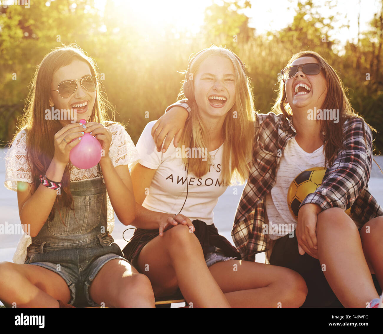 El grupo de niñas riendo mientras está sentado afuera disfrutando del verano Foto de stock