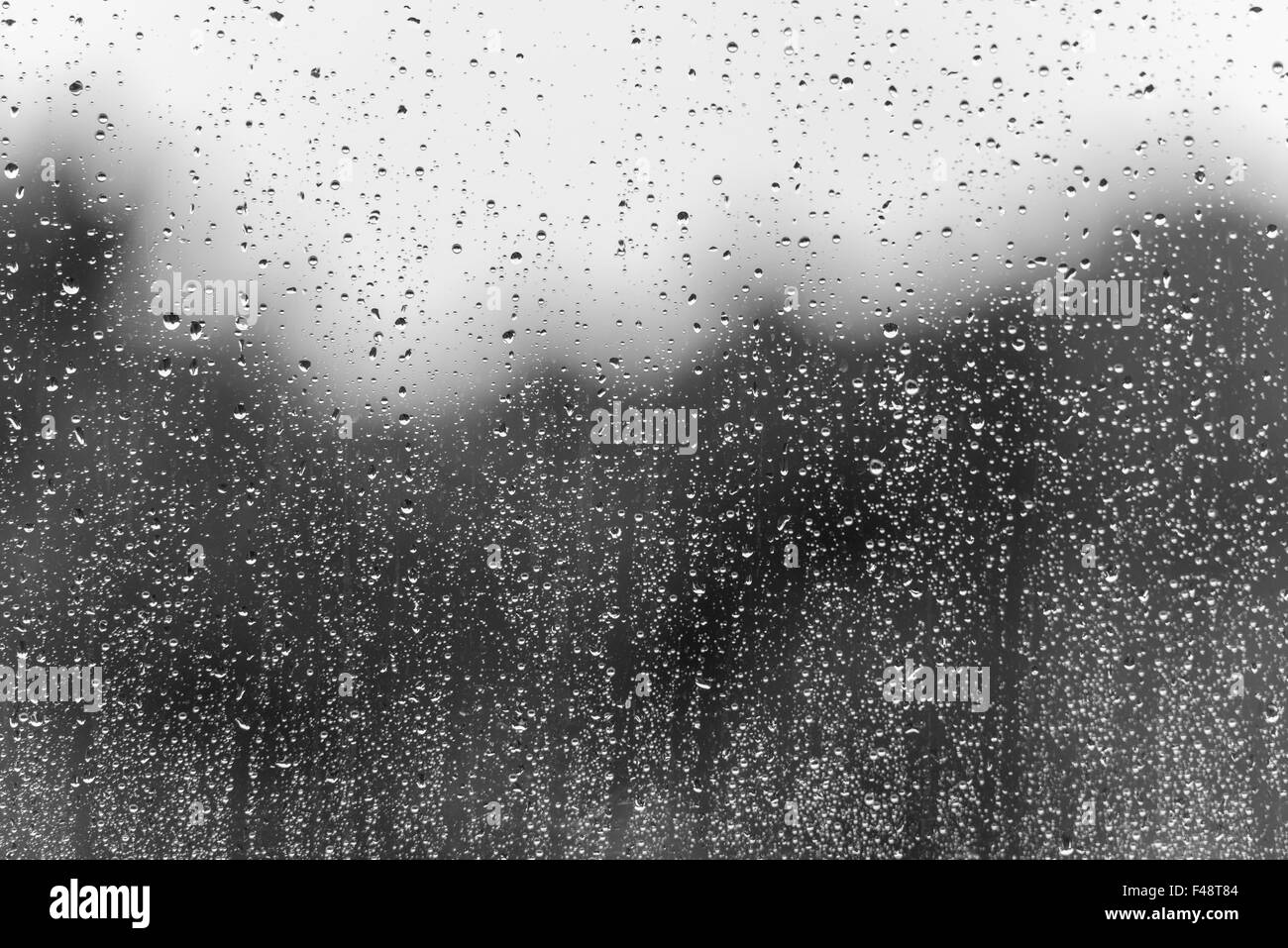 El agua de lluvia cae sobre una superficie de cristal de la ventana como un  fondo de BW Fotografía de stock - Alamy