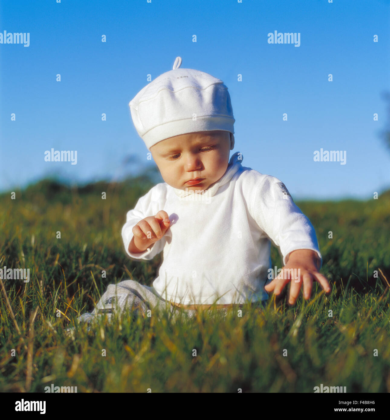 Retrato de bebé sentado en la hierba. Foto de stock